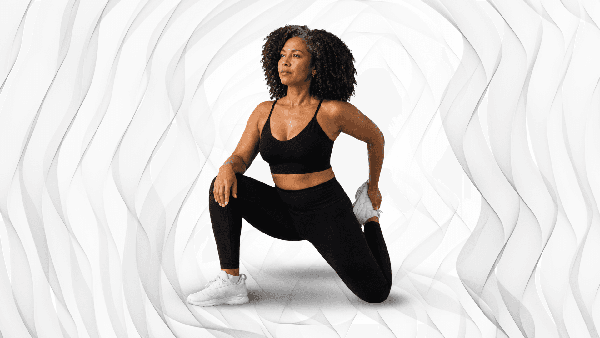 Woman in black athletic wear doing a quad stretch.