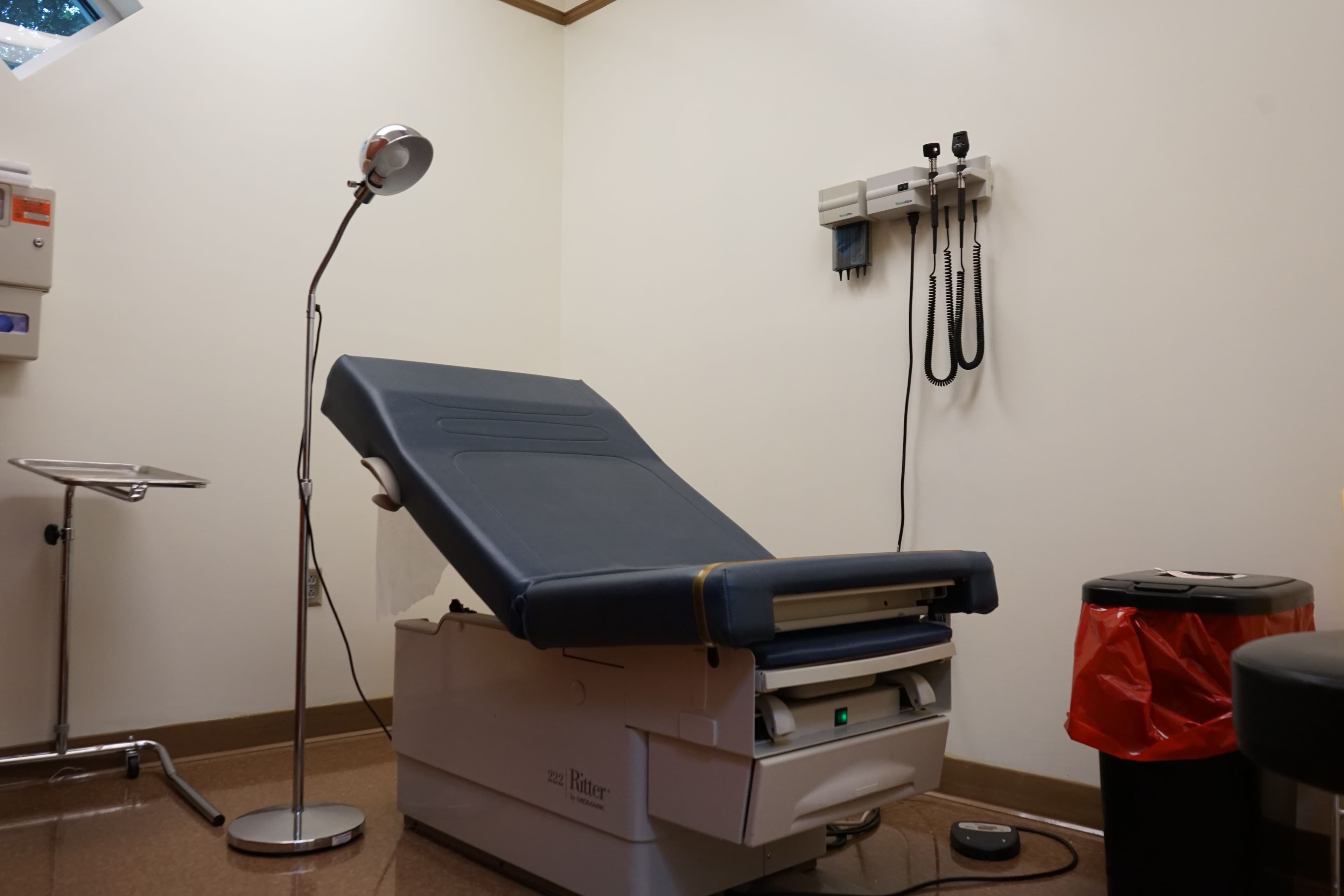 a doctor 's office with a blue exam table and a lamp .