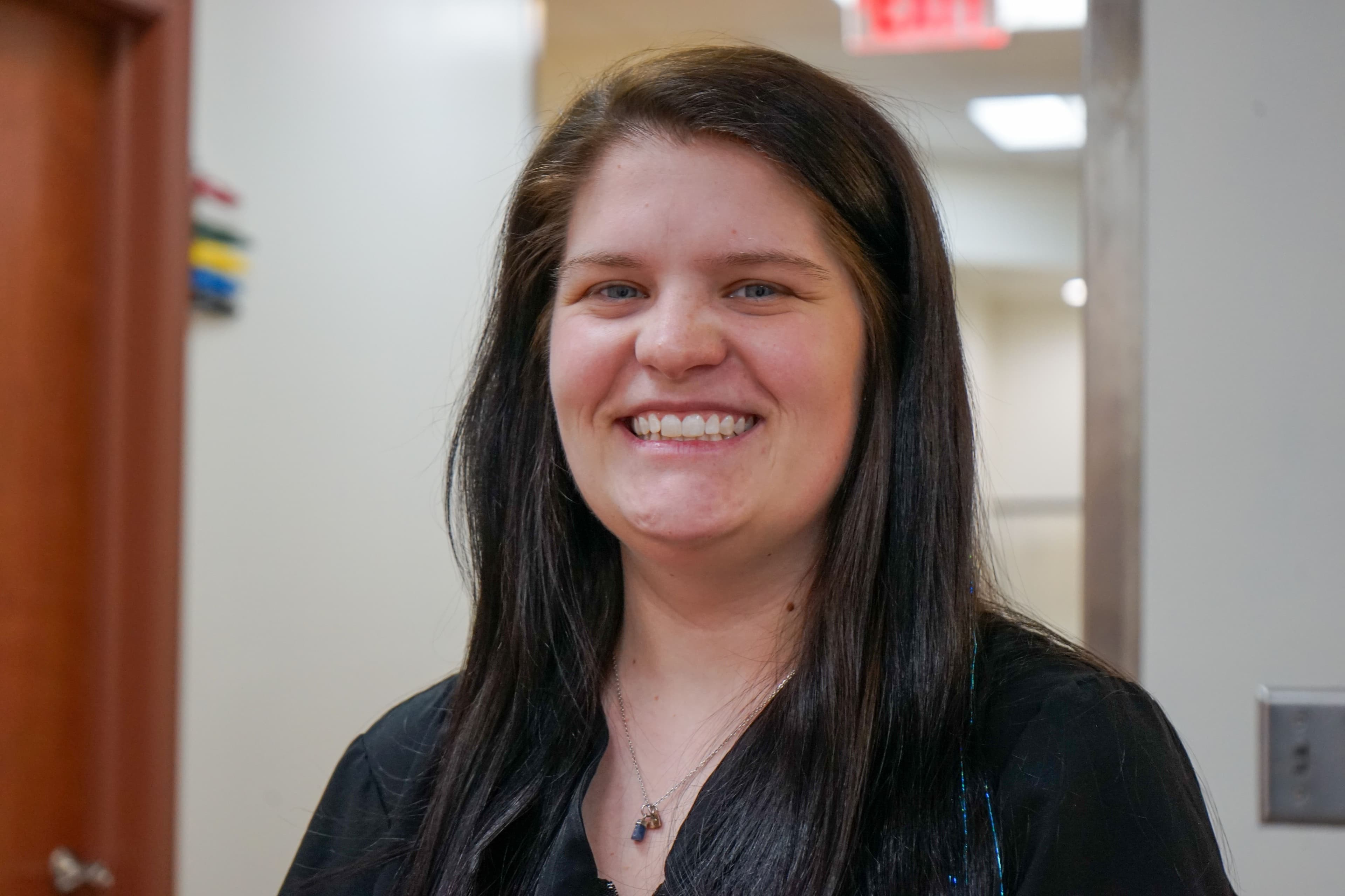 a woman with long hair is smiling for the camera in a hallway .