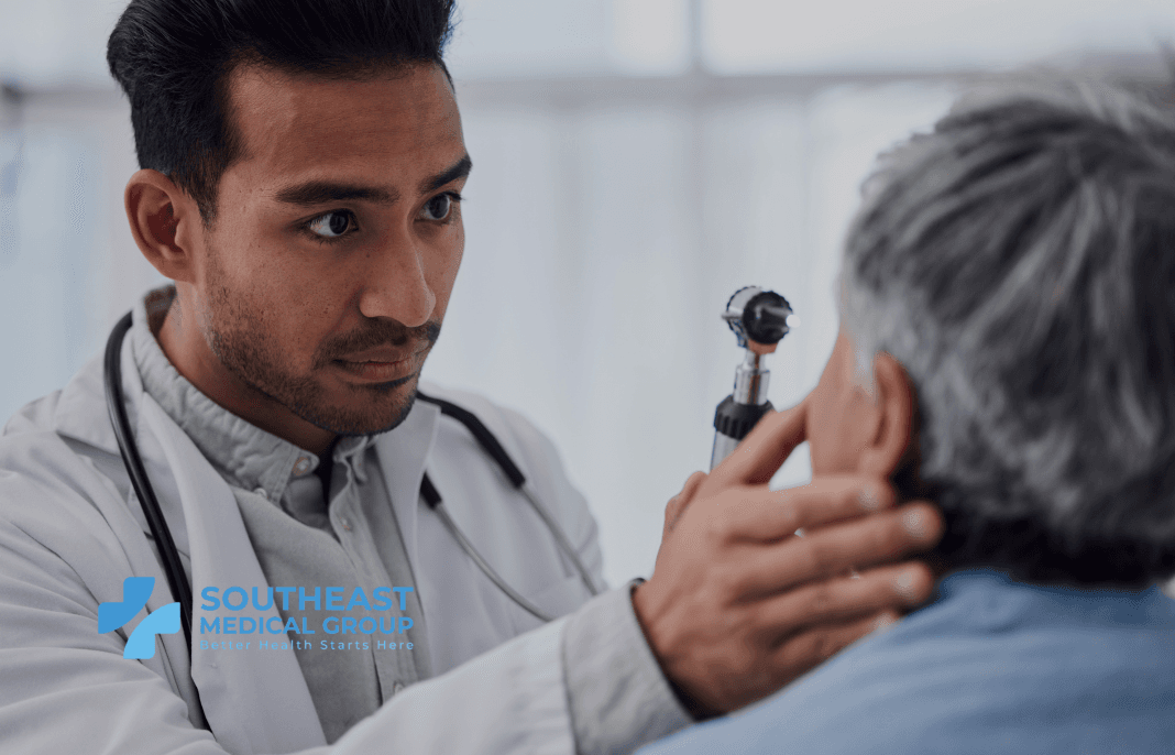 A doctor examines a patient's ear with an otoscope.