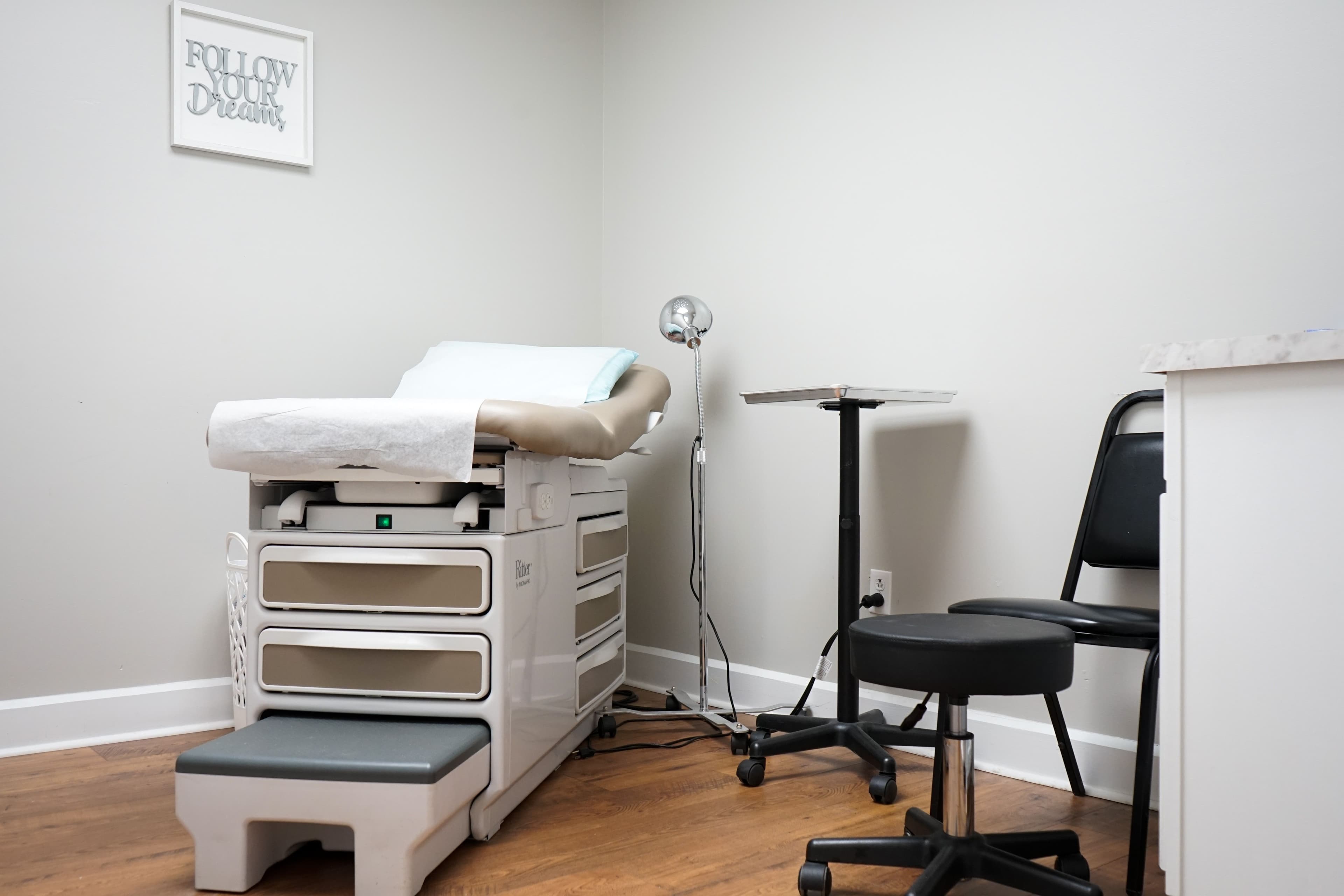 a doctor 's office with a examination table and chairs .