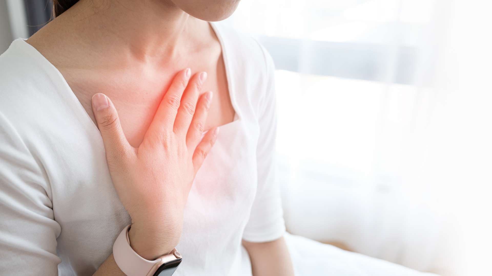 a woman is holding her chest with her hand .