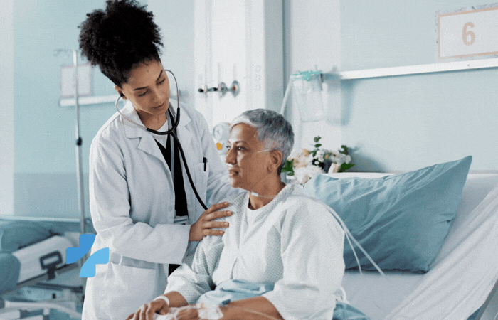 A doctor comforts a patient sitting in a hospital bed.