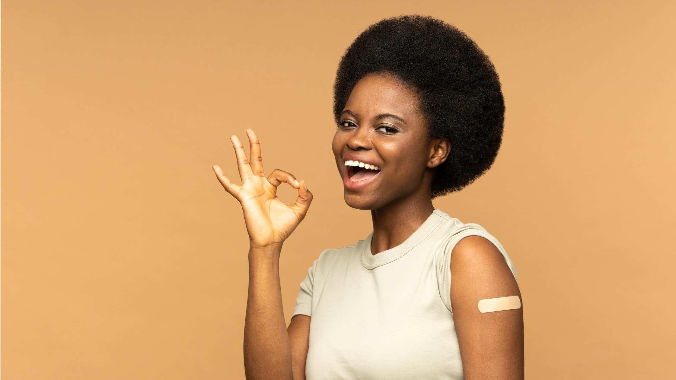 a woman after taking a vaccine dose is giving an okay sign .