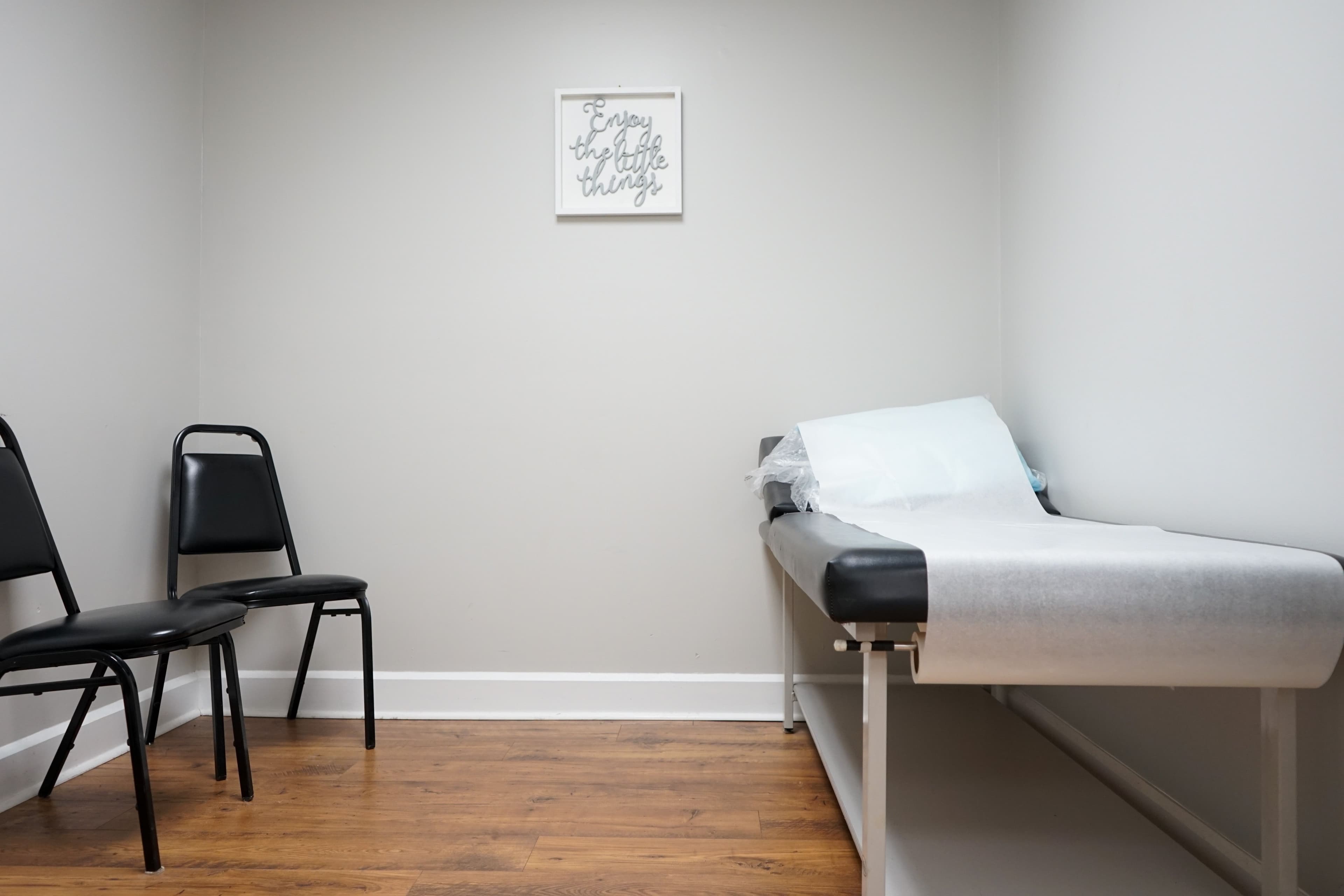 a doctor 's office with a bed , chairs and a sign on the wall .