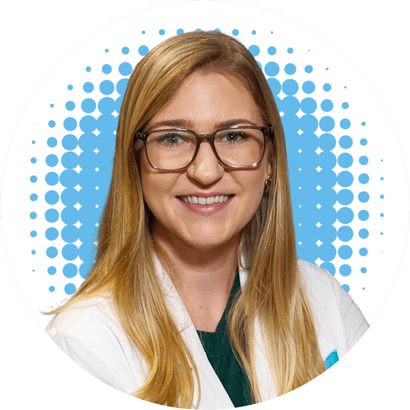 Gina Bauknecht, FNP-C, is wearing glasses and a white lab coat and smiles for the camera .