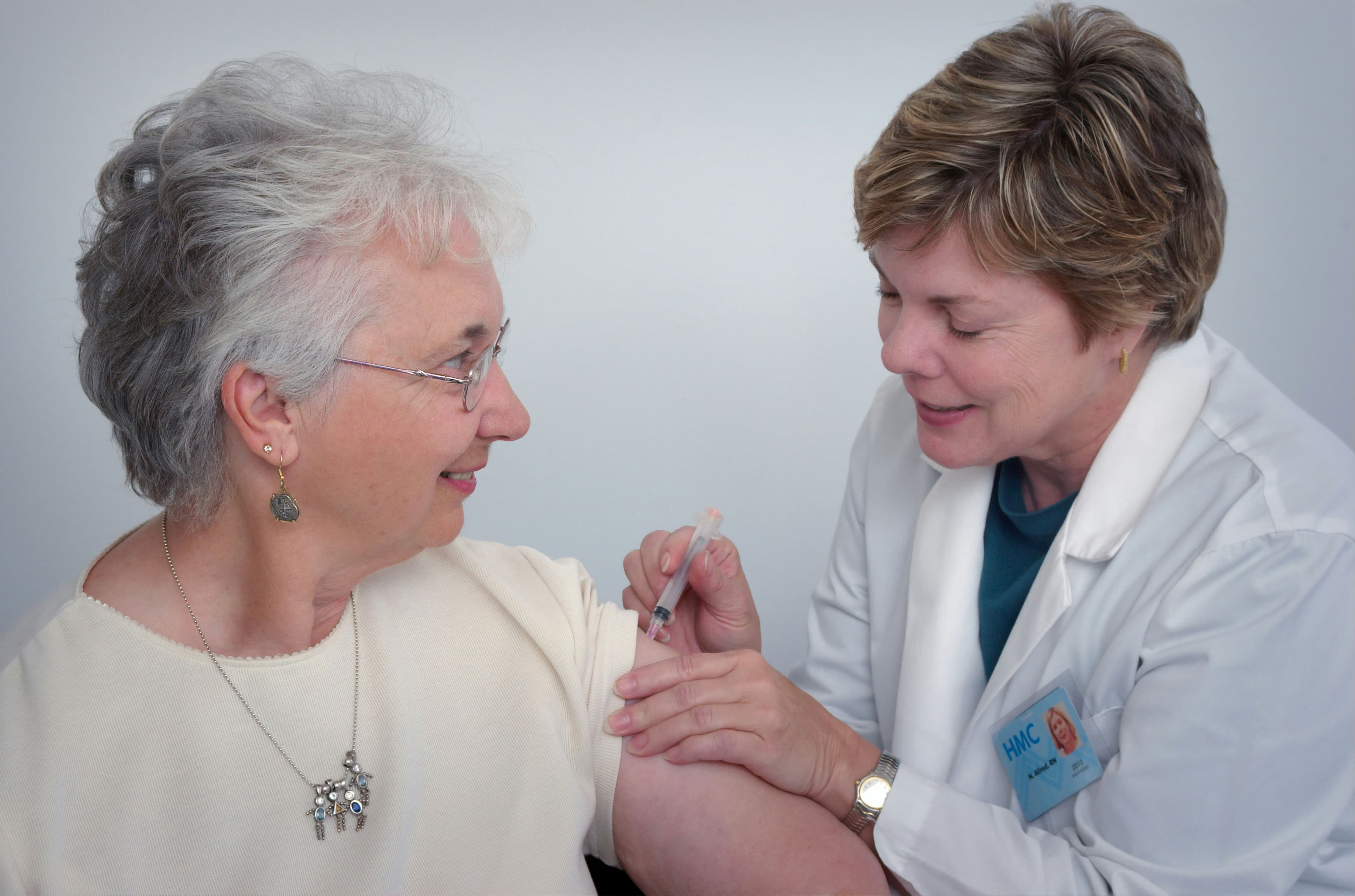 a doctor is giving an older woman an injection in her arm .