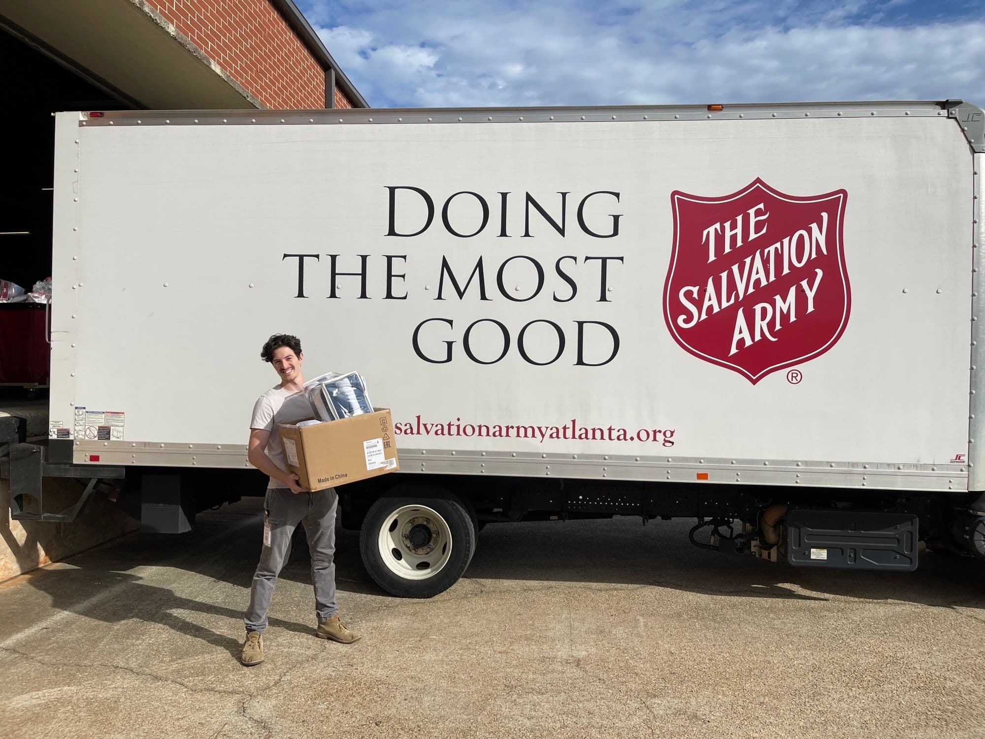 a man is holding a box in front of a salvation army truck .