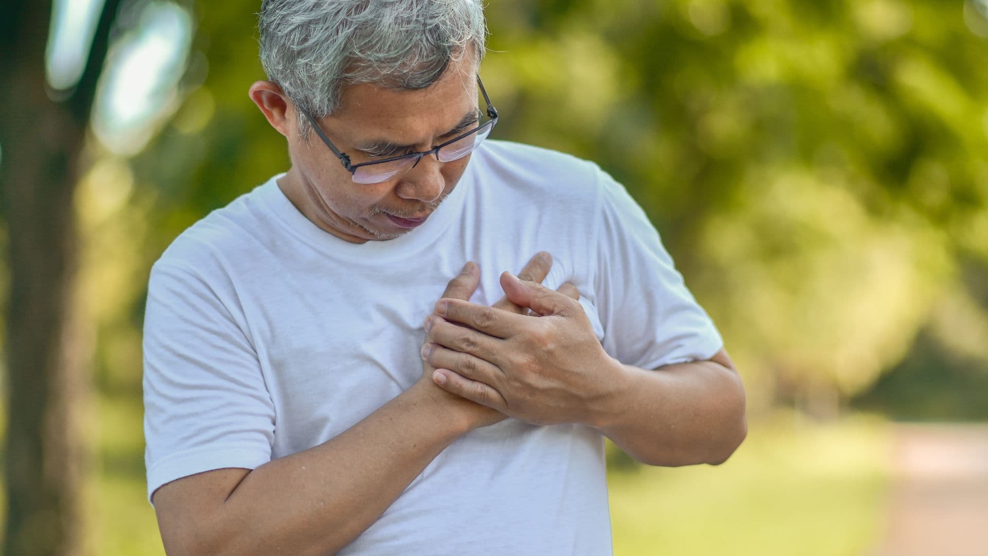 Acute Illnesses: an older man is holding his chest because he has a heart attack .