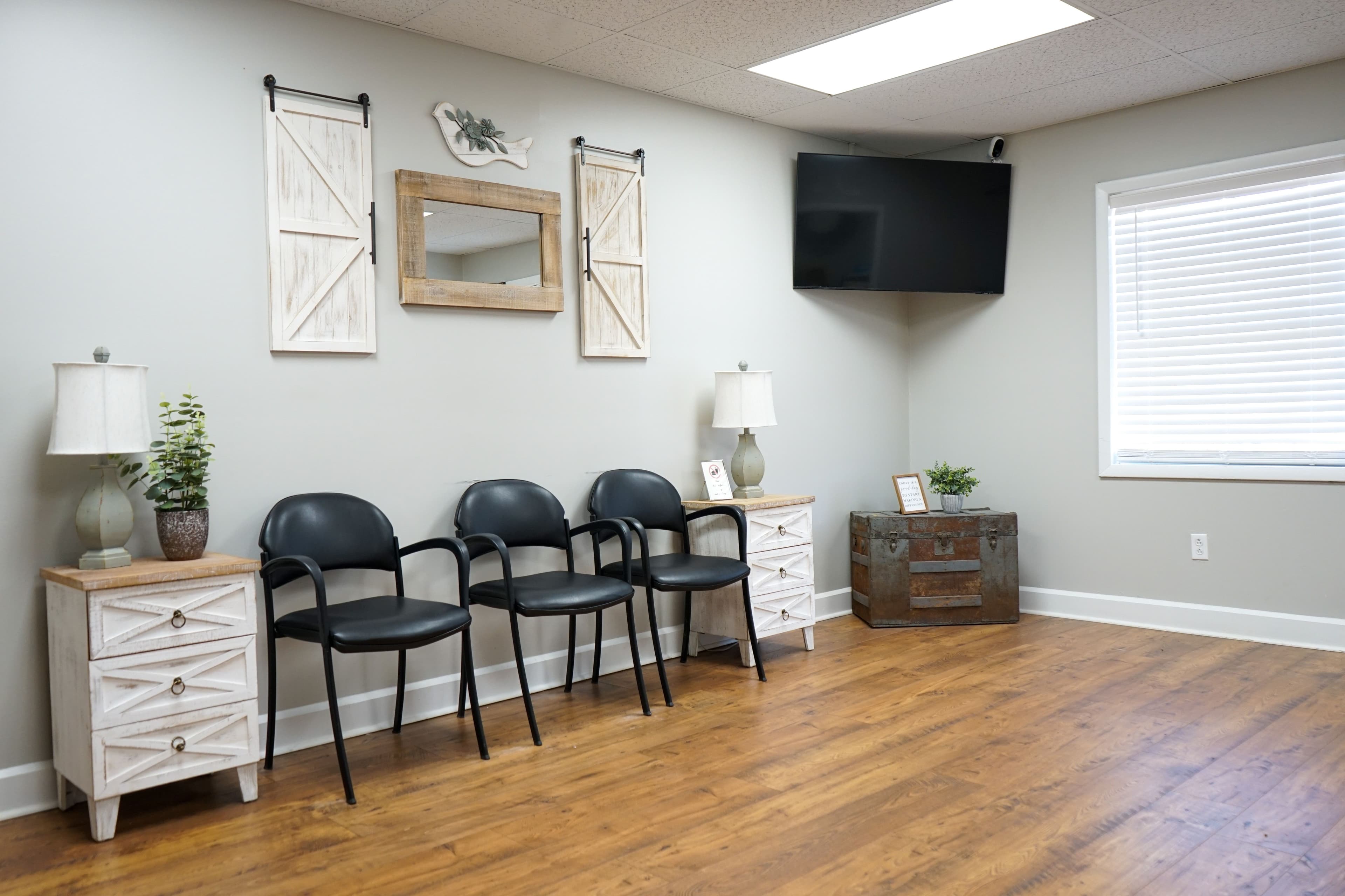 a waiting room with chairs , a television and a trunk .