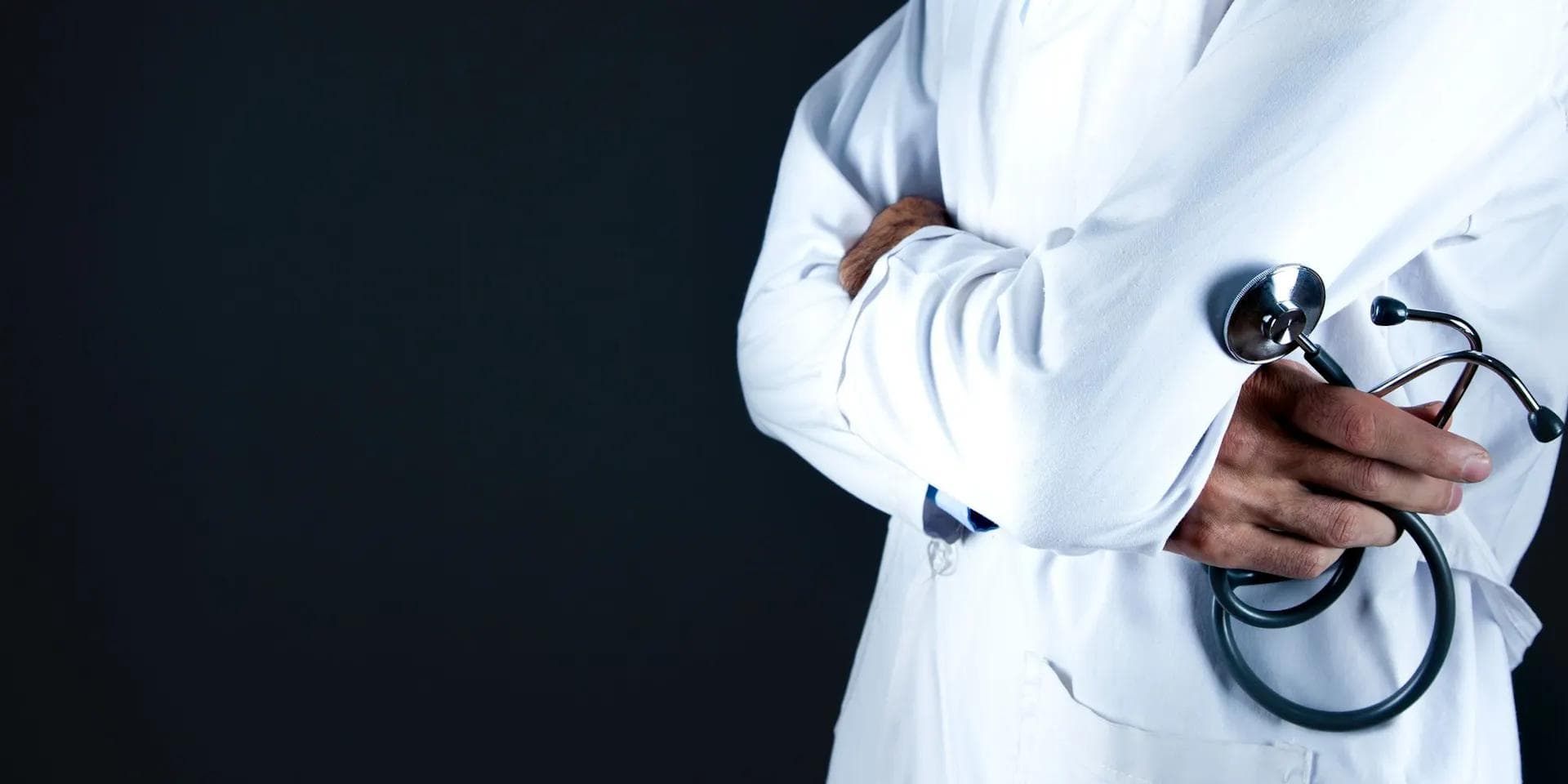 a doctor is holding a stethoscope behind his back with his arms crossed .