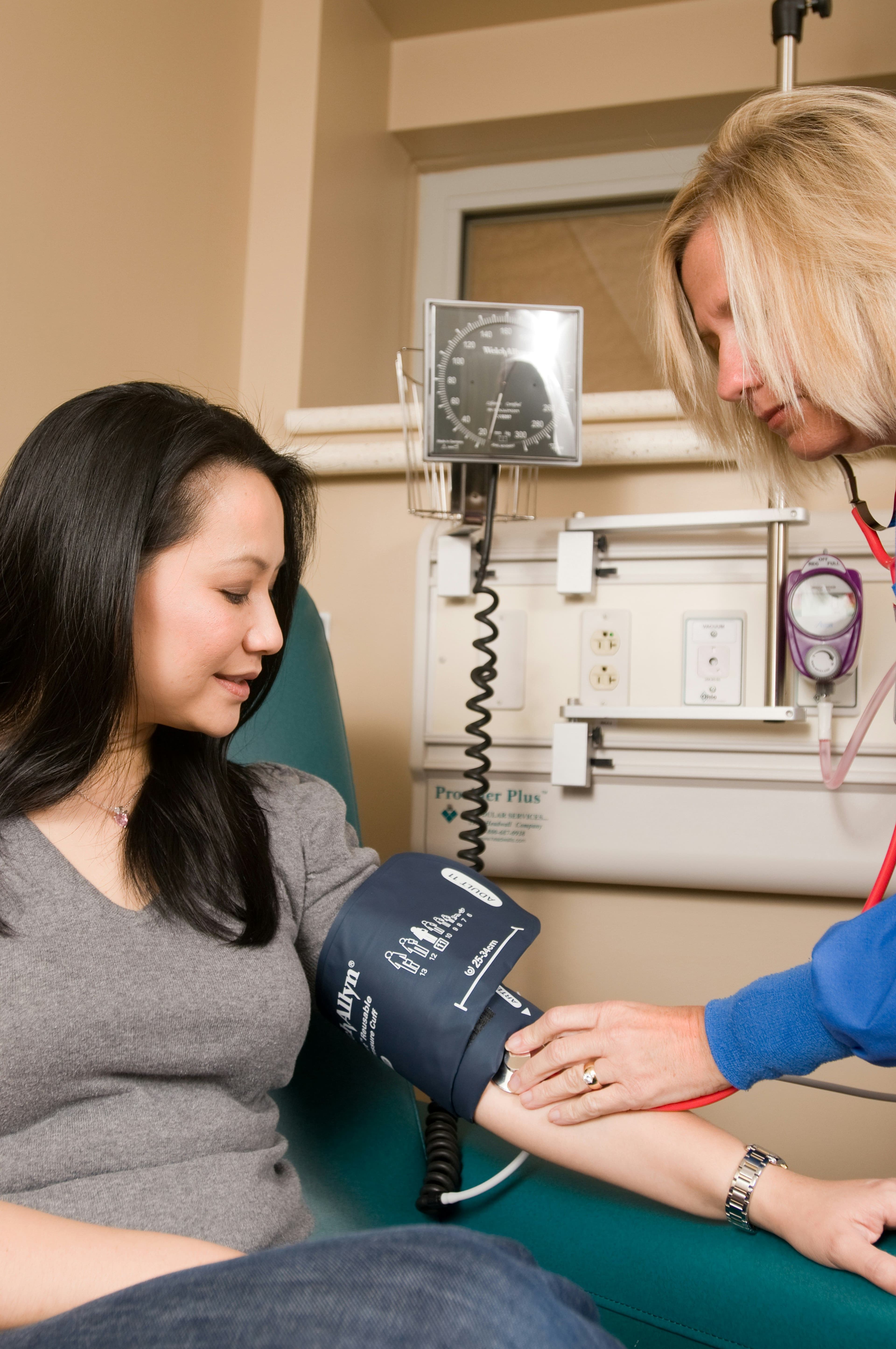 A woman getting her blood pressure checked by a female doctor .