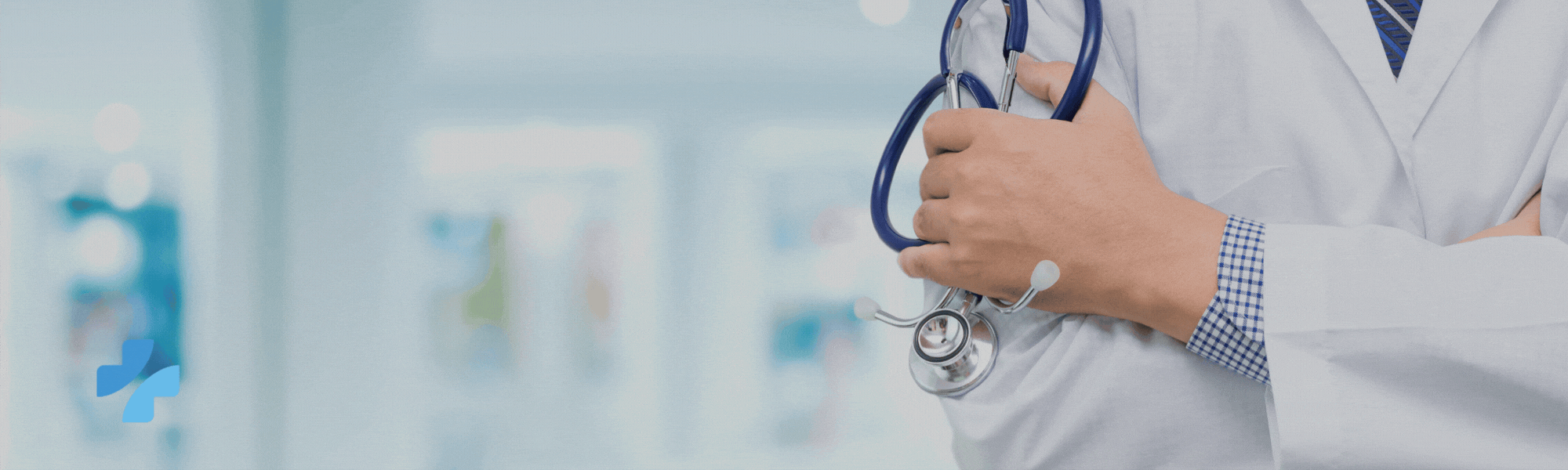 A doctor in a white coat holding a stethoscope against a blurred medical background.