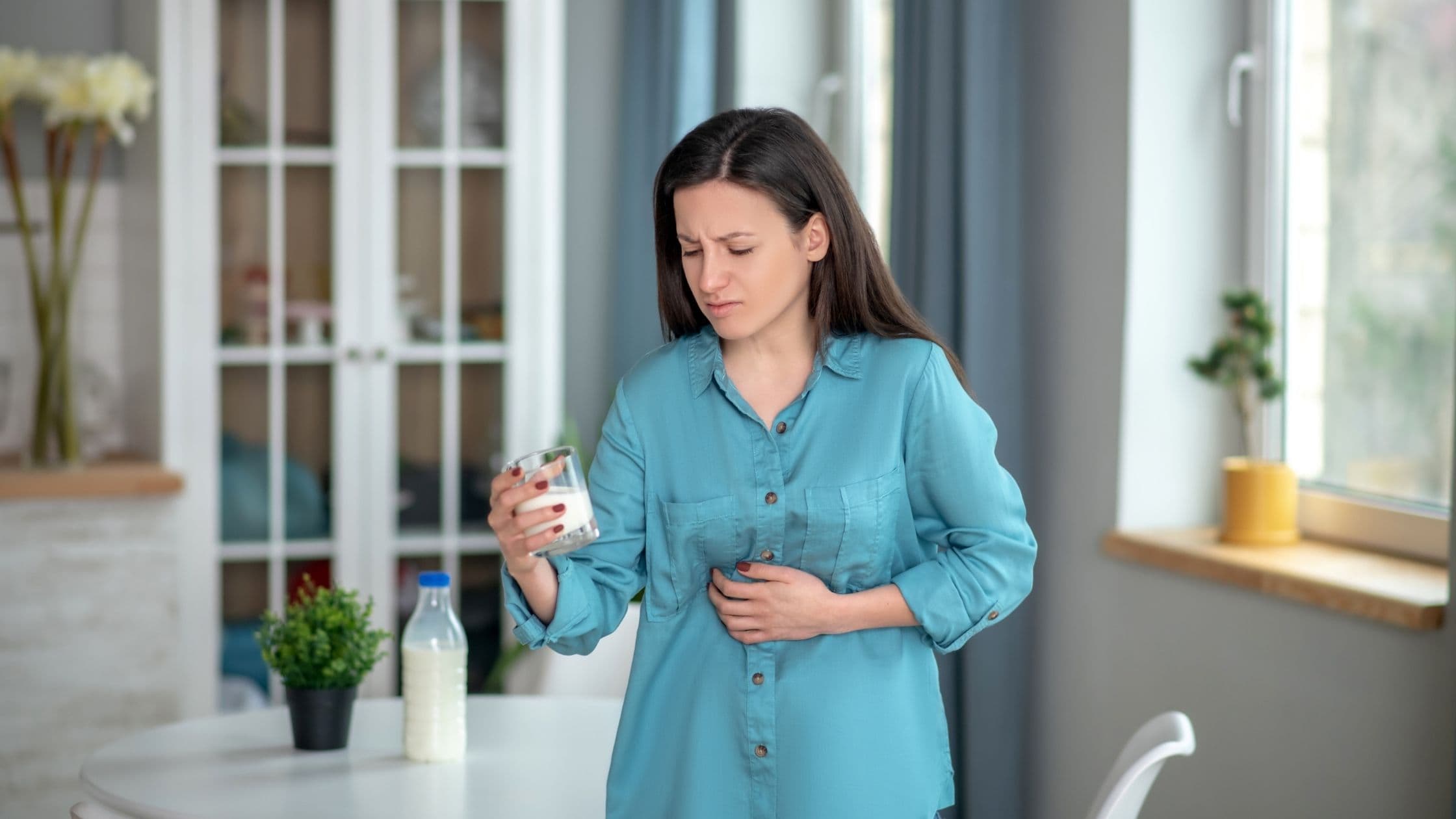 a woman is holding a glass of yogurt and holding her stomach .
