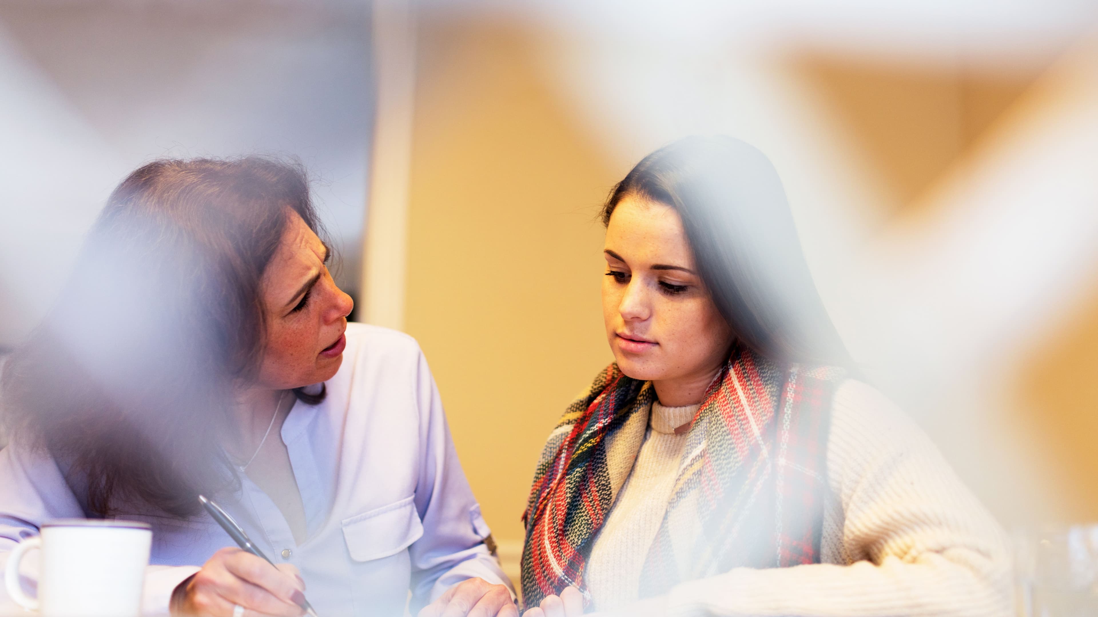 Two women engaged in a focused conversation, with one writing and the other listening.