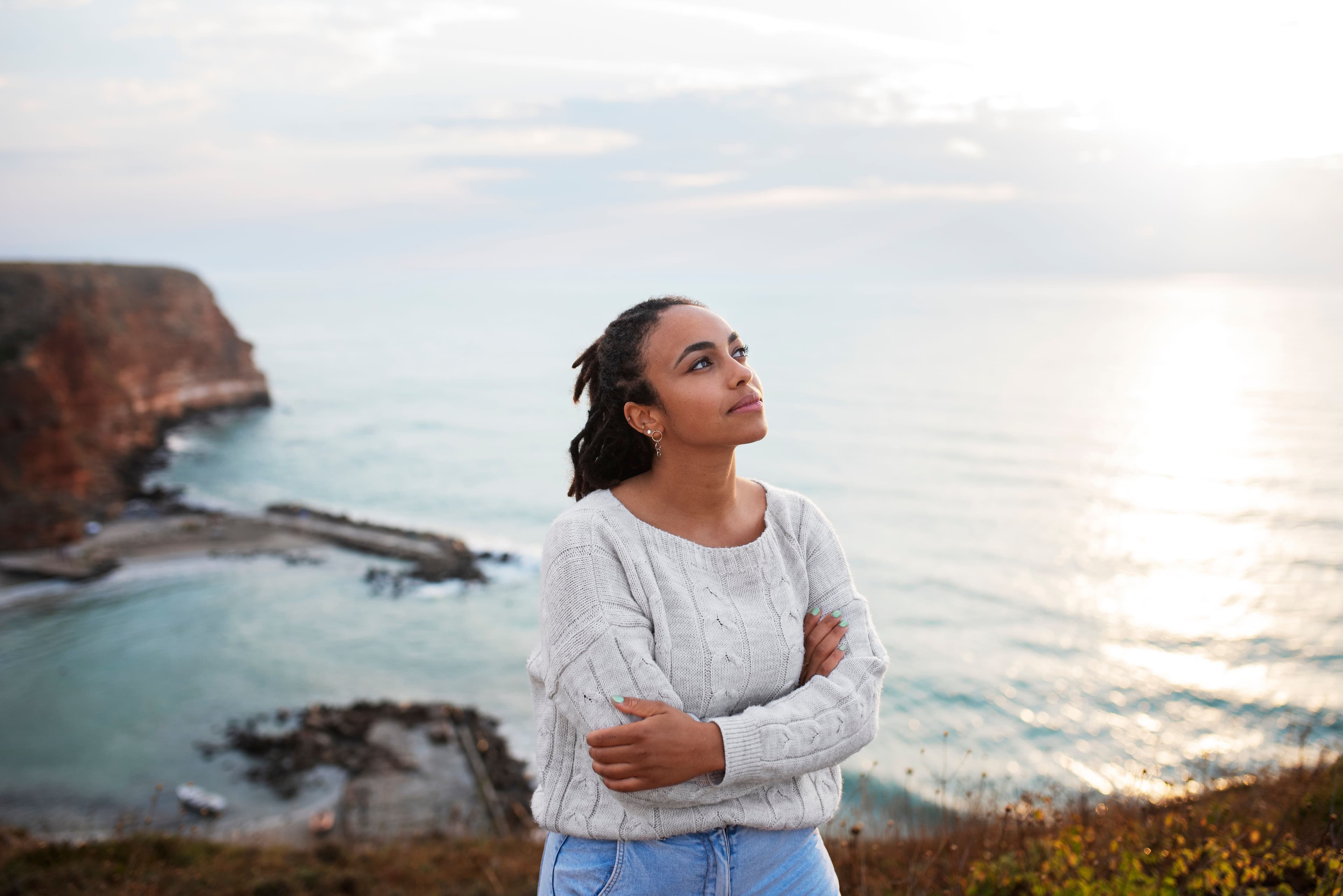 Take Care of your Mind: a woman is standing on top of a cliff overlooking the ocean.