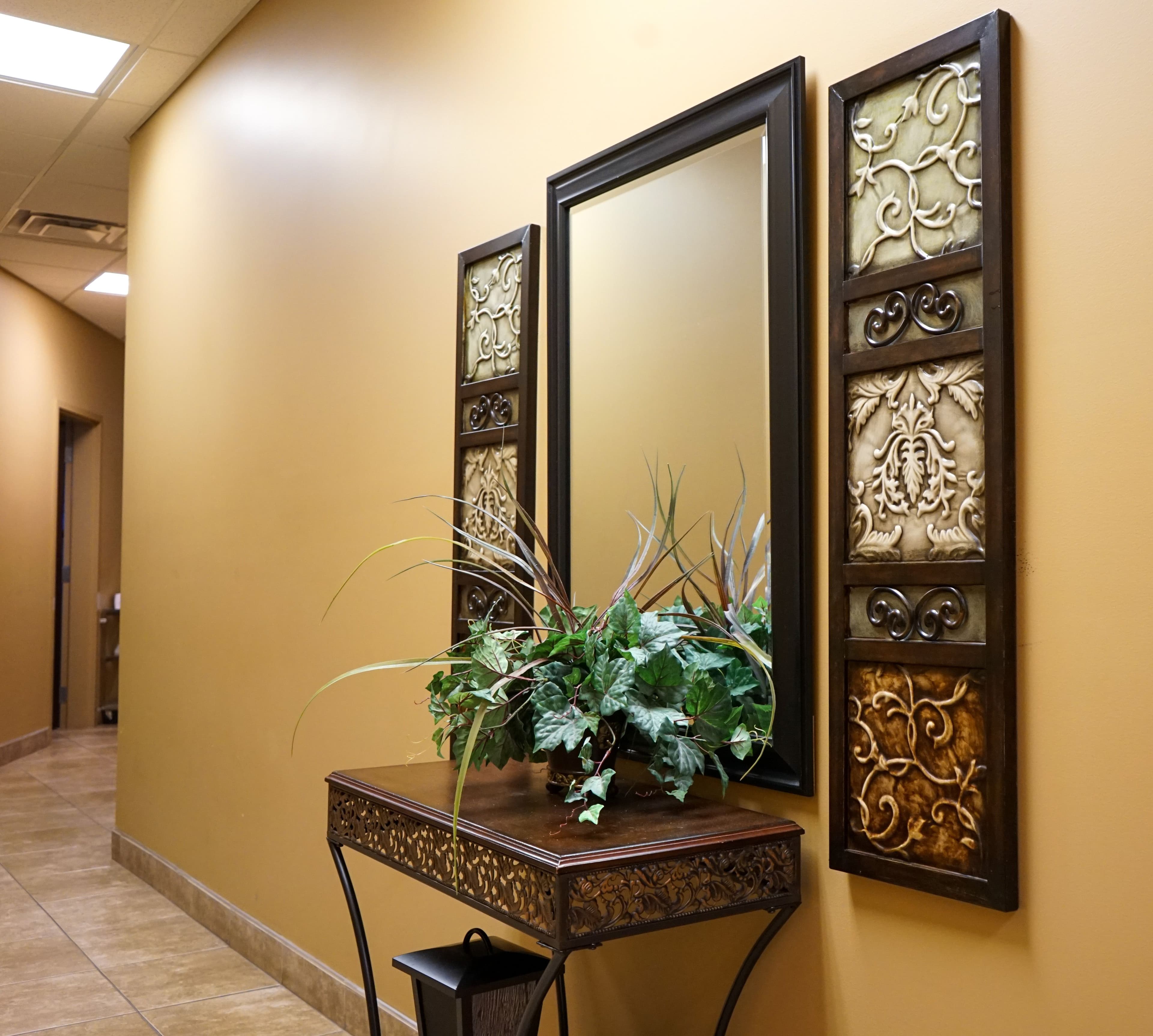 a hallway with two mirrors and a table with a plant on it .