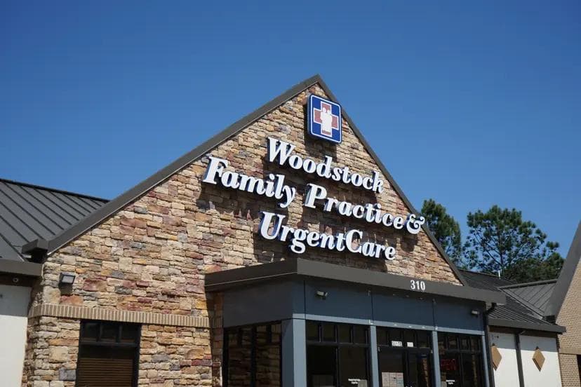 Exterior of Woodstock Family Practice & UrgentCare building with a stone facade and a prominent sign.